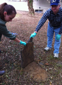 Dr. Patrick Mullins and student Emily Bielen carefully lift a fallen headstone (photo courtesy Marymount University