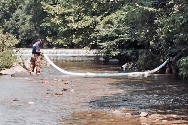 Firefighter placing a boom in Four Mile Run after a petroleum product was discovered in the water (photo courtesy ACFD)