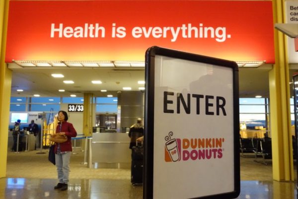 "Health is everything" sign in front of Dunkin' Donuts sign at Reagan National Airport (Flickr pool photo by Kevin Wolf)